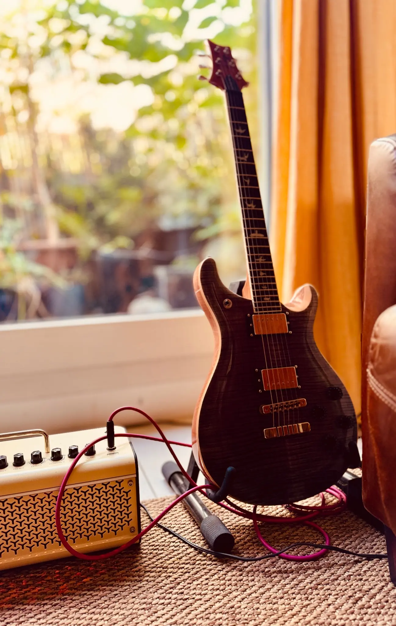 Electric guitar and amplifier in warm window light