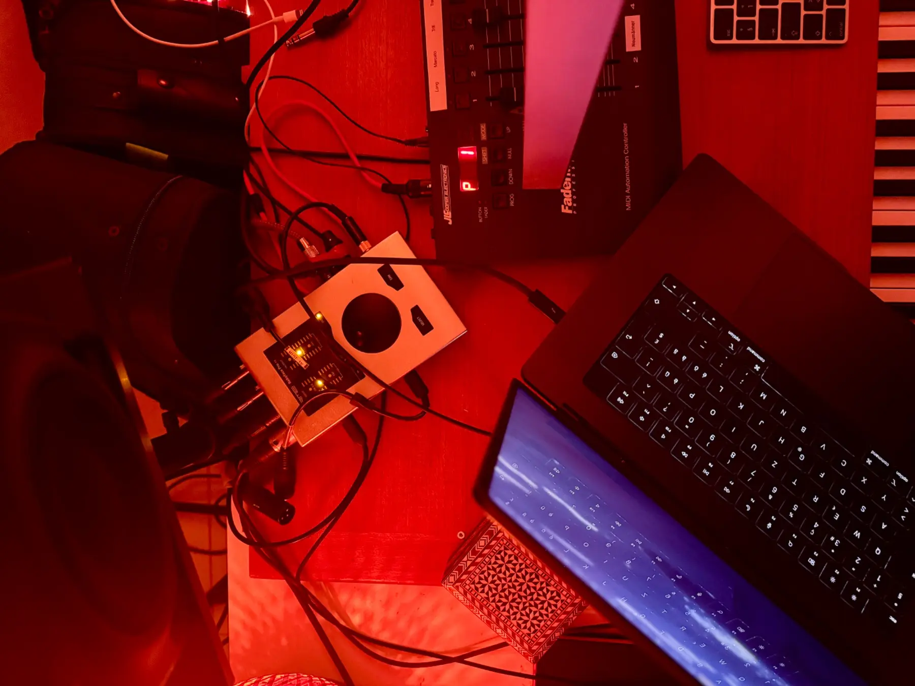 Laptop and audio equipment on the studio desk at night